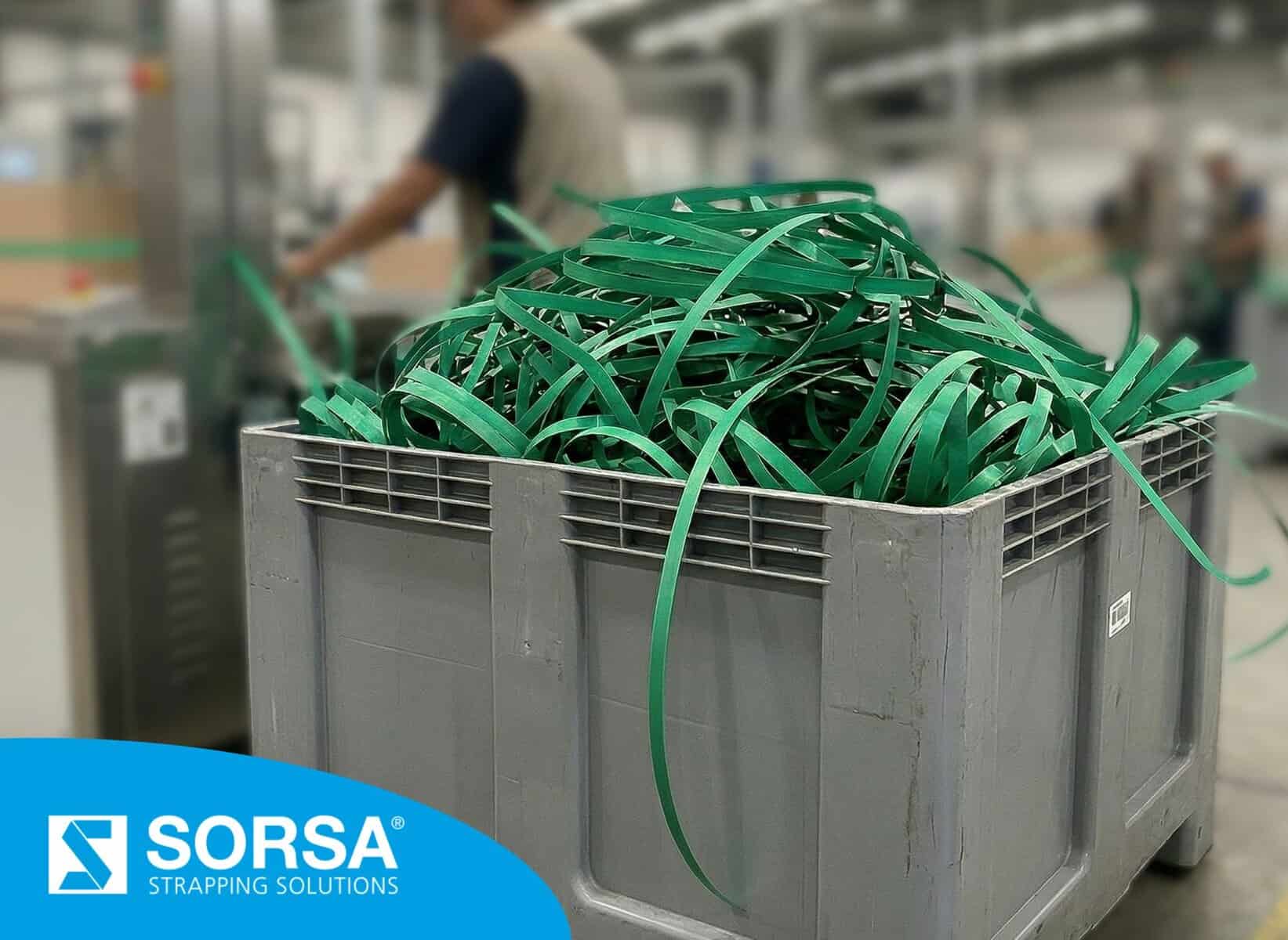 Industrial container with green strapping waste accumulated due to failures in automatic strapping machine.